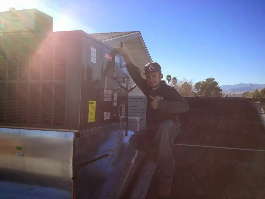 HVAC technician performing AC Tune-Up on a rooftop unit in Gray